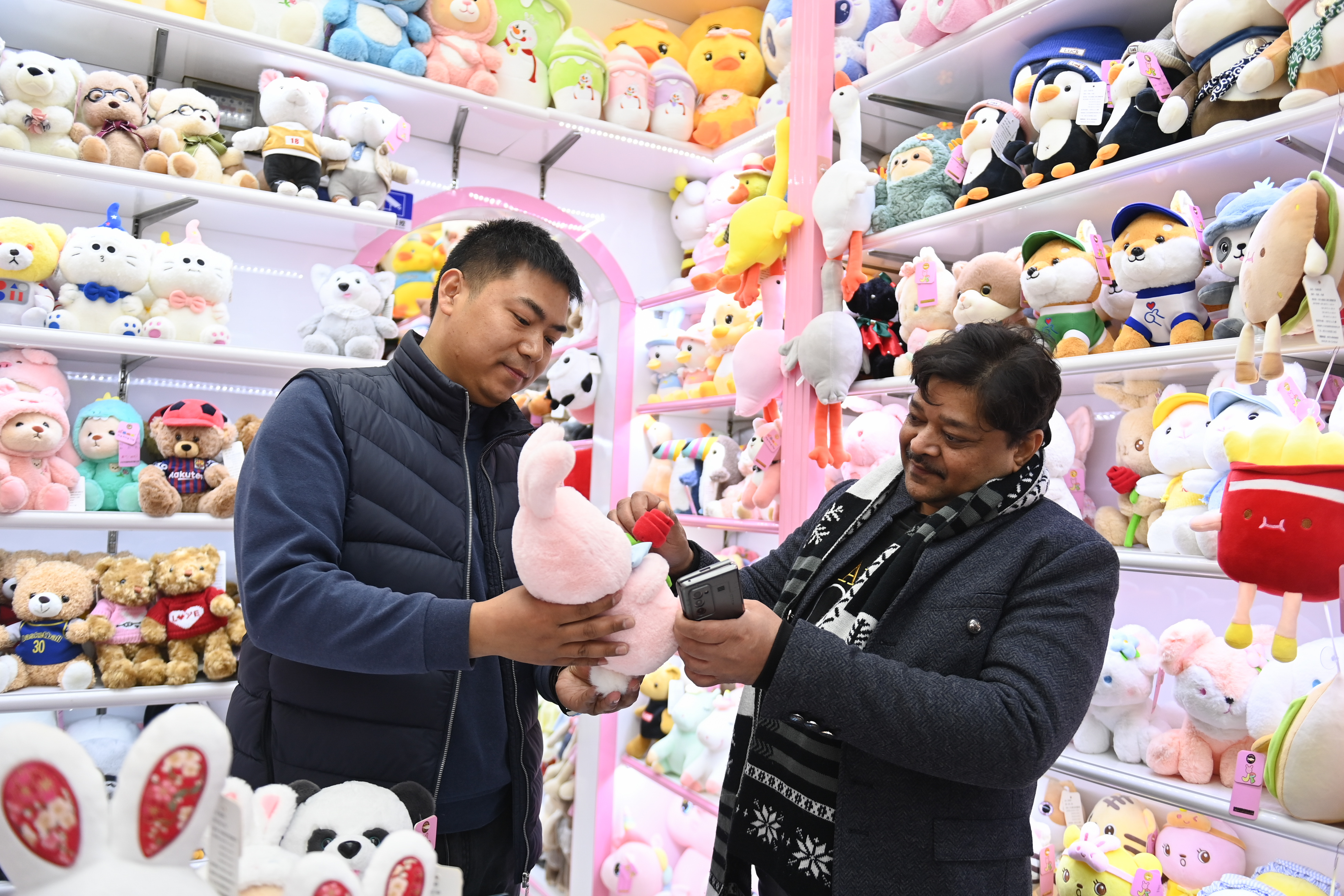 2023年2月2日，來自印度的客商（右）在義烏國際商貿(mào)城的一家玩具店鋪內選購。